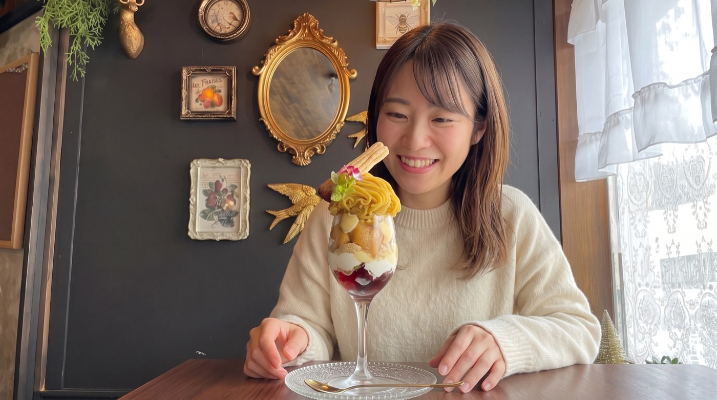 風のアリアの店内で、テーブルの琥珀のアリアを笑顔で見つめる女性
